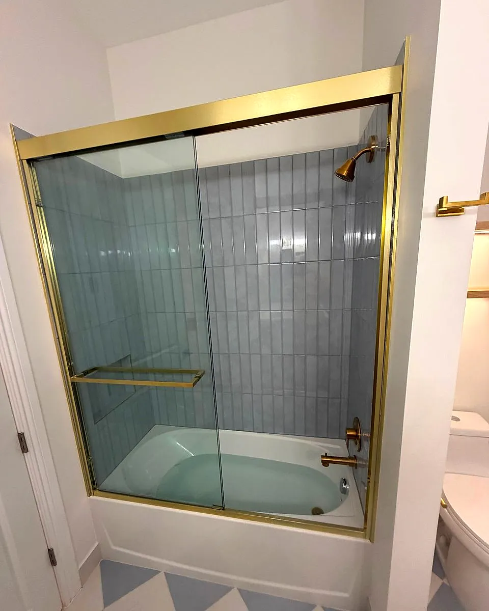 Finished tub with blue-gray tile and a gold-framed sliding glass door