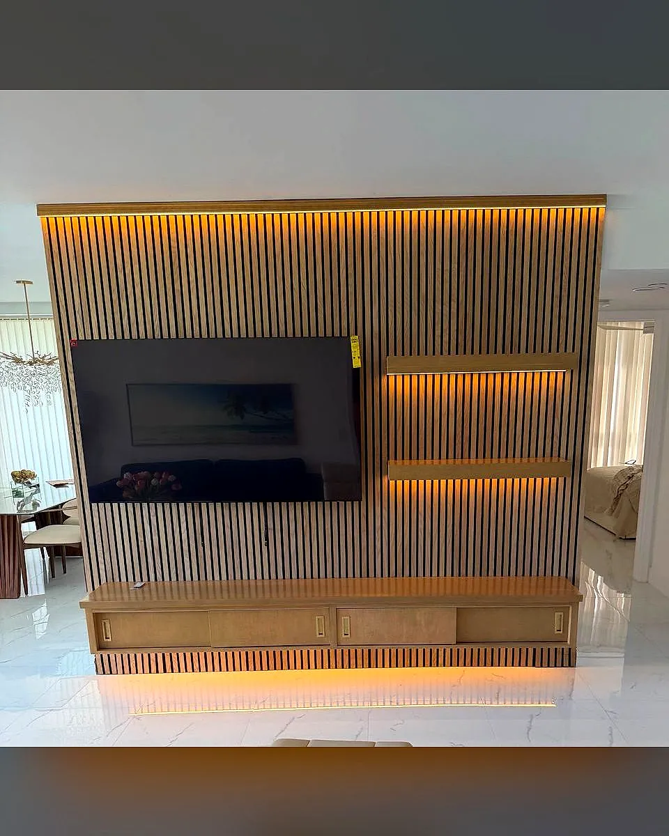 Wood slat accent wall with a mounted TV, floating shelves and warm lighting