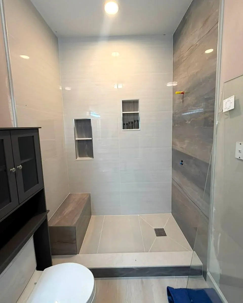 Finished walk-in shower with niches, a bench and a wood-look feature wall